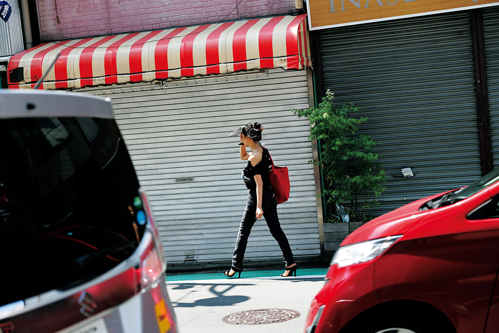 Pejalan kaki yang menyandang tas merah terabadikan bersama mobil warna merah dan nuansa merah