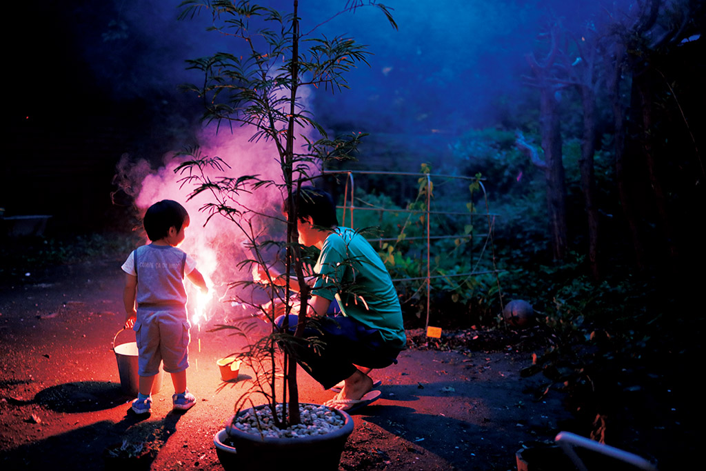 Parent and child playing with sparklers at night